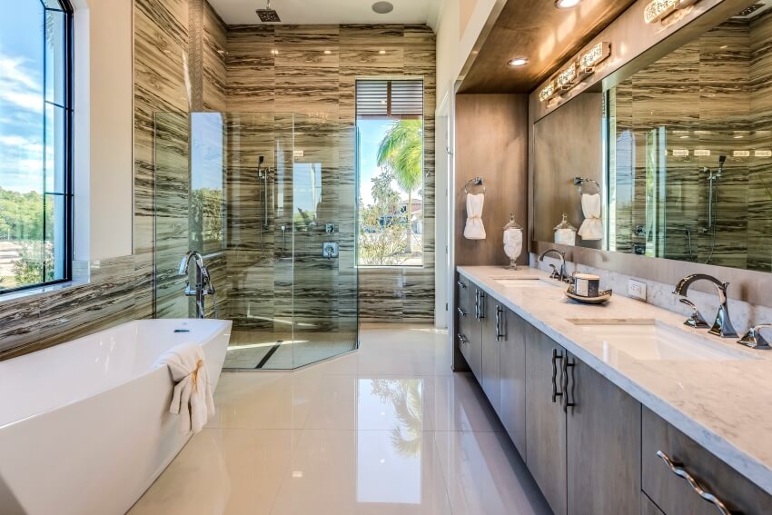 Отдельно стоящая кварцитовая столешница и большая стеклянная душевая кабина в роскошной главной ванной комнате.