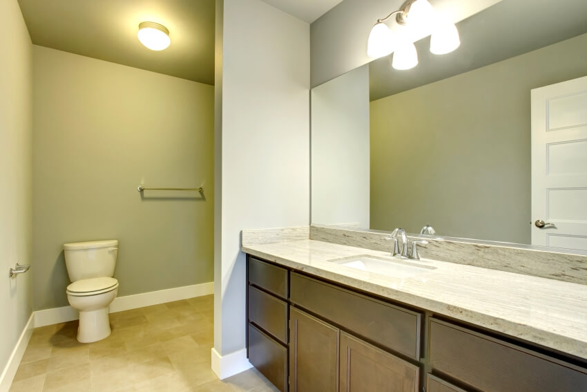 Интерьер ванной комнаты с бра, кафельным полом, большим зеркалом и столешницей из кварцита