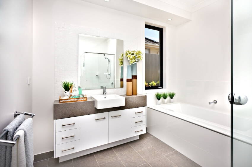 Ярко-белая ванная комната с одной раковиной, ванной, кафельным полом и окном.