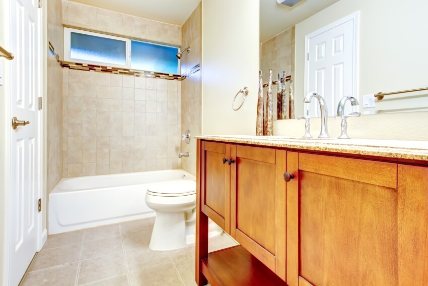 Белый интерьер ванной комнаты с отделкой стен и пола кафельной плиткой и туалетным столиком из цельного дерева