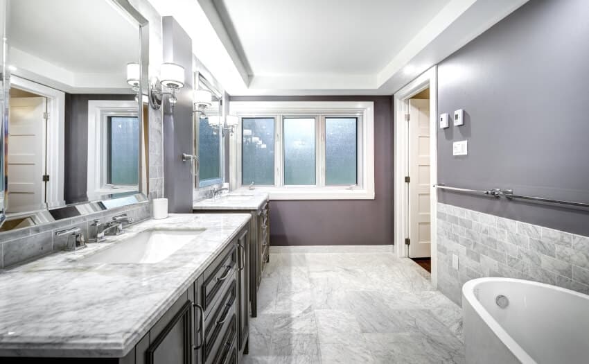 Ванная комната с мраморным полом и столешницей, серой стеной, окнами и бра