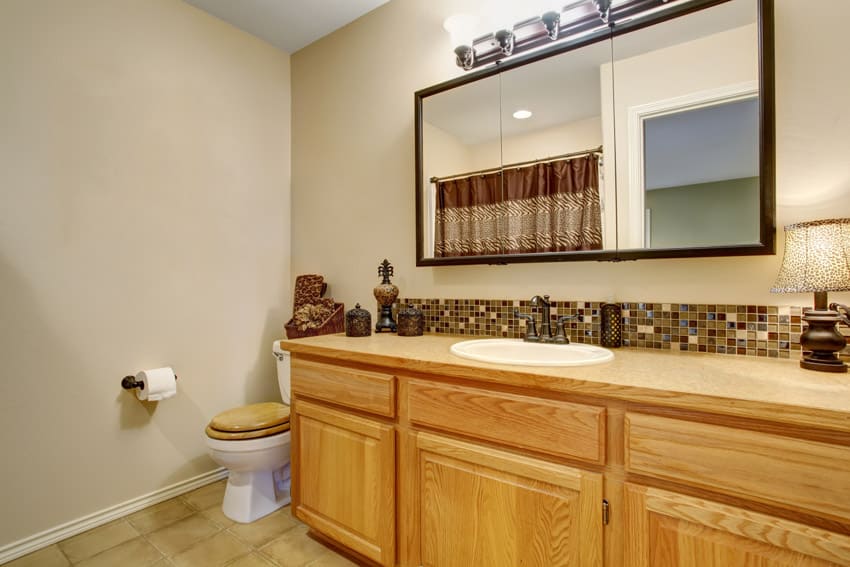 Ванная комната со шкафами из медового дуба, туалетным столиком, зеркалом, столешницей и унитазом.