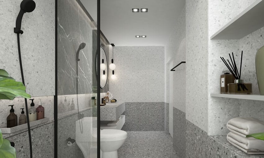 Серая ванная комната с душевой стеной из терраццо, насадкой для душа, туалетом и зеркалом