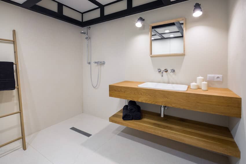 Ванная комната с белой стеной, душем, столешницей из мясного блока, зеркалом и настенными светильниками.