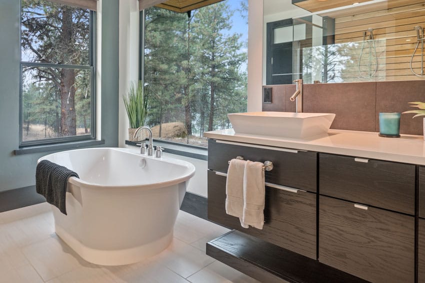 Ванная комната с панорамными окнами, плавающим туалетным столиком, ванной и зеркалом.