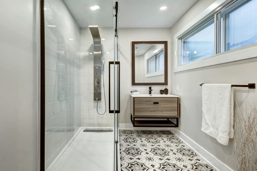 Ванная комната с узорчатыми виниловыми полами, плавающей раковиной, стеклянной дверью, душевой, современной насадкой для душа, зеркалом и окнами.