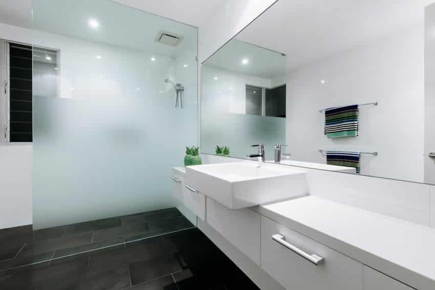 Ванная комната с плавающей раковиной, белой раковиной, зеркалом, стеклянной перегородкой и душевой кабиной.