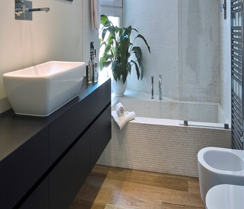 Интерьер ванной комнаты с деревянным полом, черной плавающей столешницей и зеркалом с трековой подсветкой