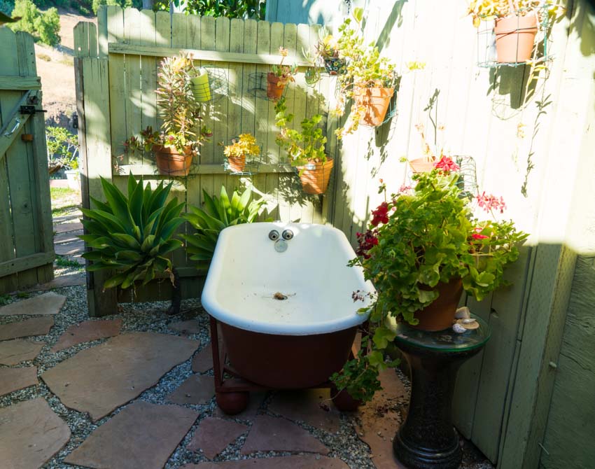 Сад с ванной, мощеной дорожкой и цветами