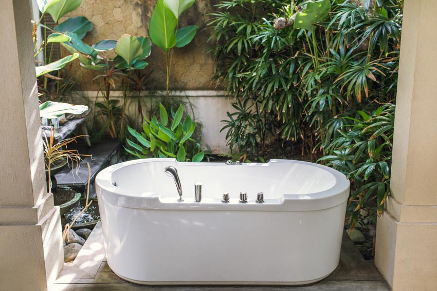 Ванна на открытом воздухе с белой ванной и растениями