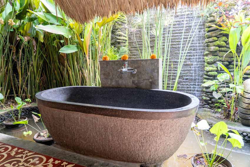 Красивая открытая ванна с каменной ванной, краном и растениями