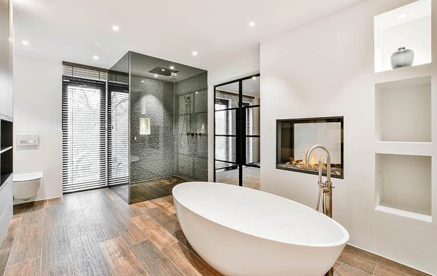 Роскошная современная ванная комната с душевой кабиной из угольного стекла, отдельно стоящей ванной и кафельным полом под дерево