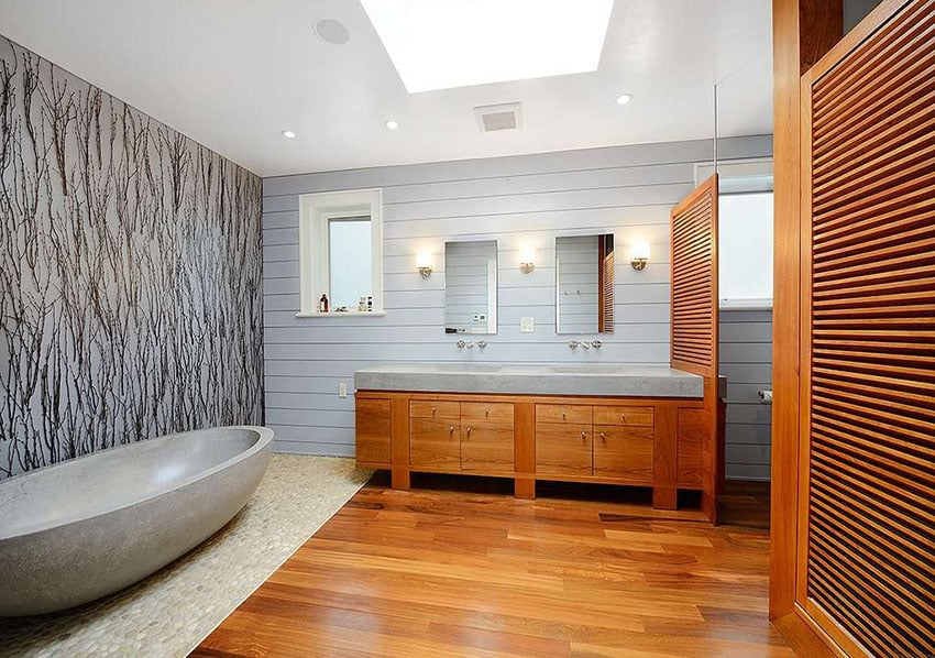 Современная главная ванная комната с изготовленной на заказ ванной из травертина и полом из натурального речного камня.