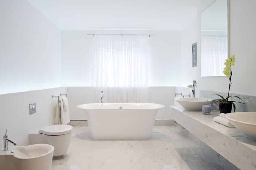 Полностью белая современная ванная комната с отдельно стоящей ванной