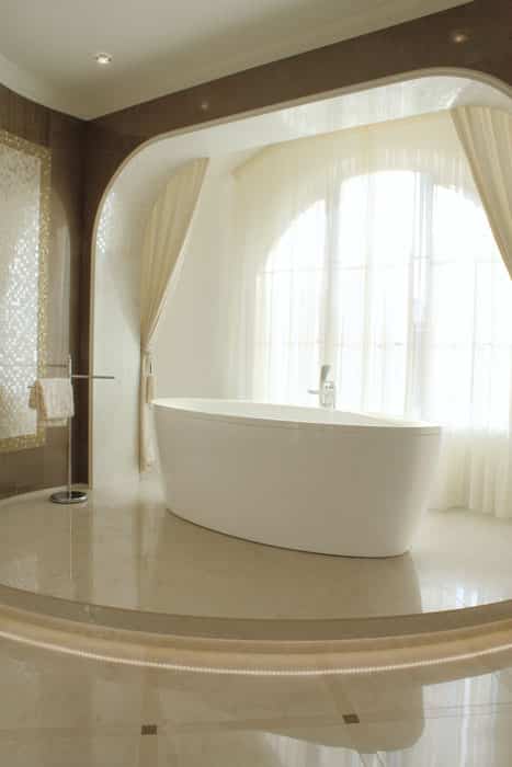 Современная минималистская ванная комната с ванной на возвышении и большим окном