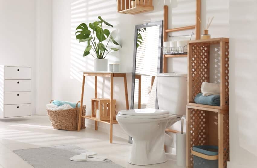 Просторная ванная комната с деревянным хранилищем на столе, зеркалом и вешалкой для салфеток над унитазом