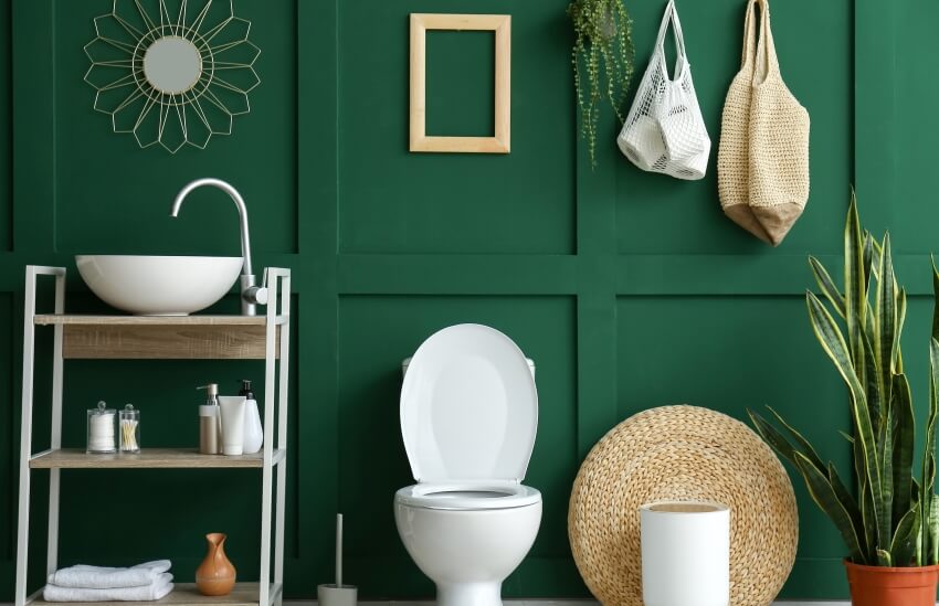 Туалет с полками для унитаза, растениями и декором на зеленой стене панели