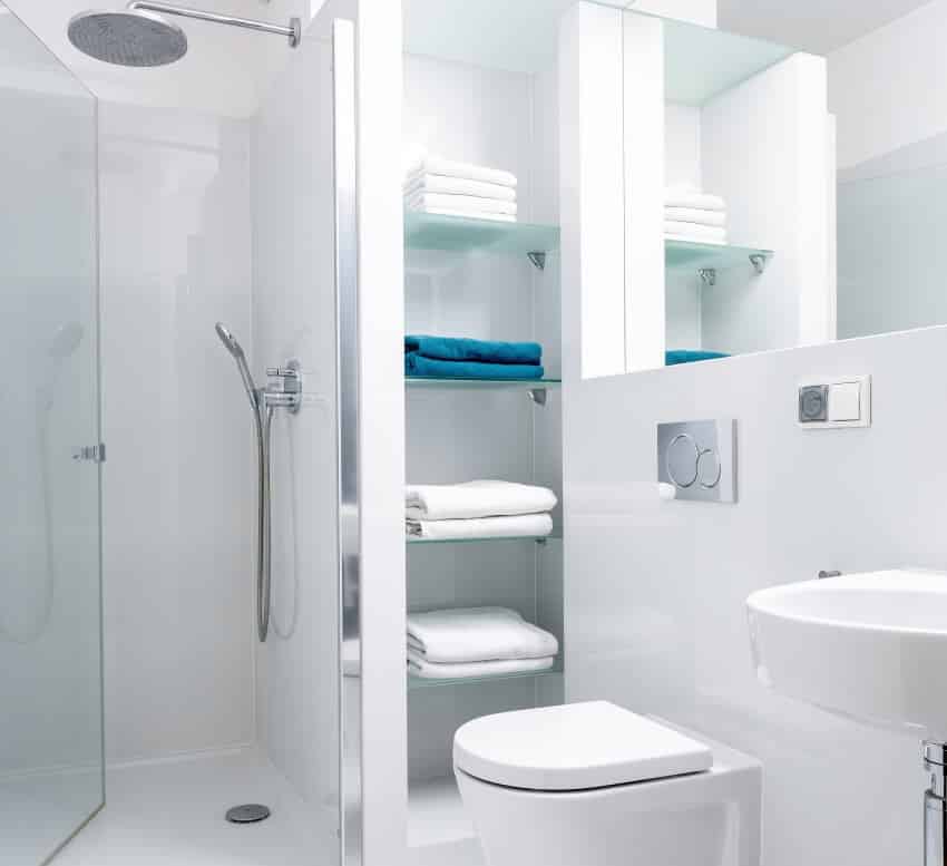 Ярко-белая ванная комната с полками для душа и зеркалом над унитазом и раковиной