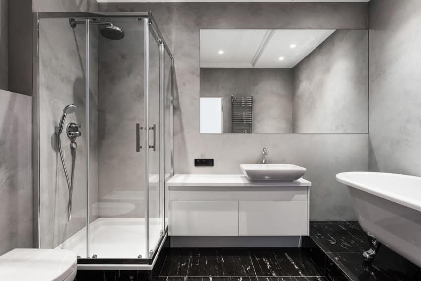 Ванная комната с чугунным поддоном для душа и душевой стеной из каменной смолы