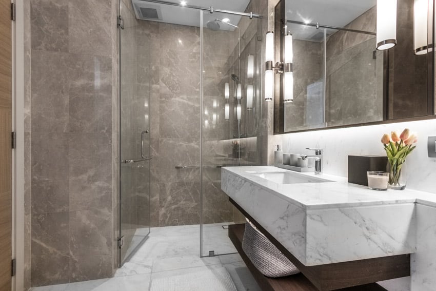 Ванная комната с душем из каменной смолы, стеклянной дверью, мраморной раковиной и зеркалом.