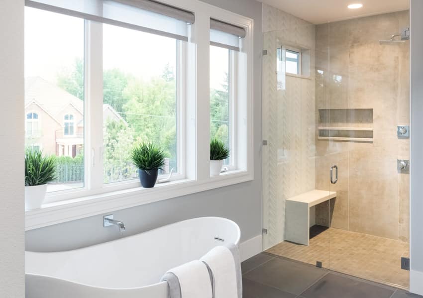 Ванная комната с душевой стеной из каменной смолы, ванной, окнами и встроенными светильниками