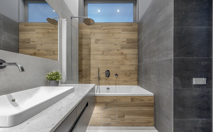 Минималистский интерьер ванной комнаты с ванной и душем с темной каменной плиткой и текстурой деревянной стены
