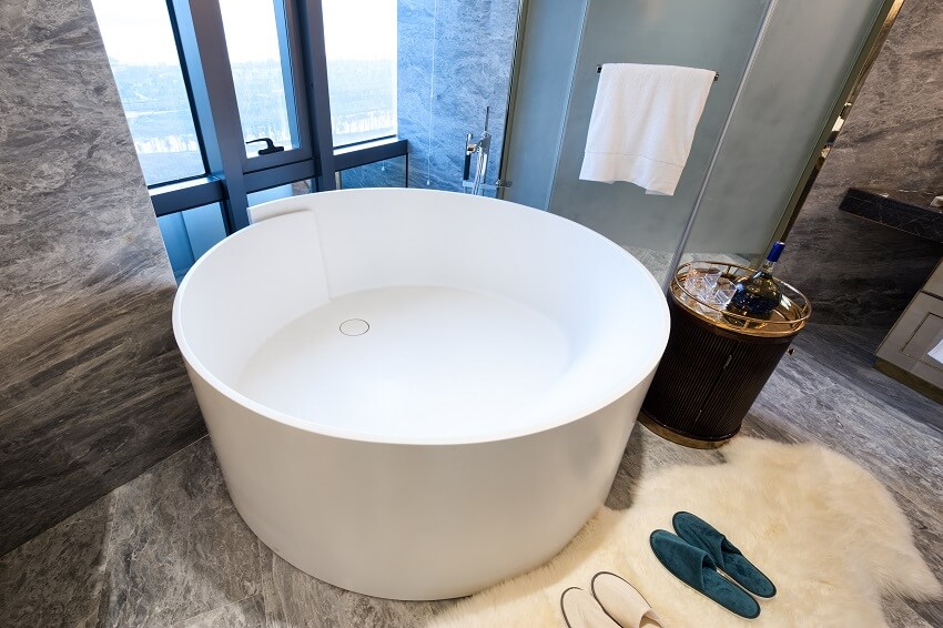 Роскошная ванная комната с ванной в японском стиле, меховым ковриком, стенами и полом, выложенными мраморной плиткой.