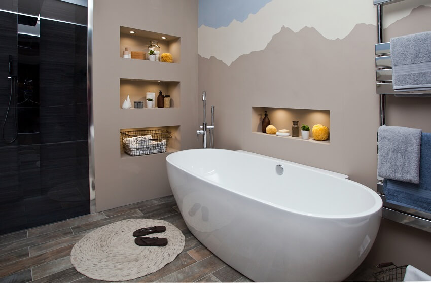 Интерьер ванной комнаты с утопленными настенными полками, вешалками для полотенец и ванной