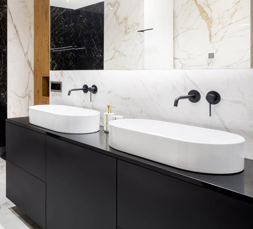 Stunning bathroom with white marble tiles, mirror washbasins and granite countertop