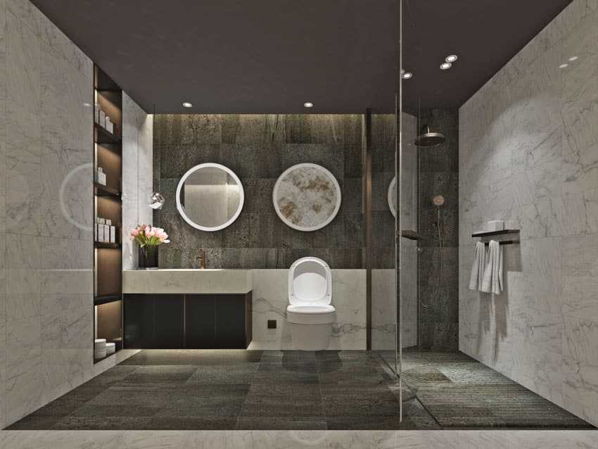 Ванная комната со стенами из каменной смолы, душевая, пол из сланцевой плитки, зеркала, туалет и раковины.