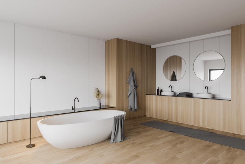 Minimalist bathroom with laminate wood floors, mirror, sink tub, and white walls