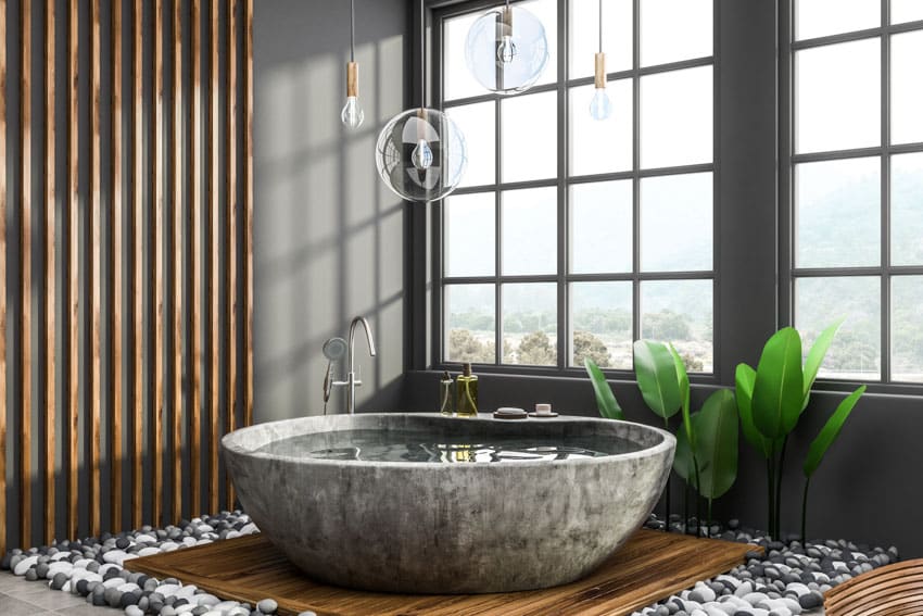 Ванная комната с каменной ванной, деревянной акцентной стеной, комнатными растениями и окнами