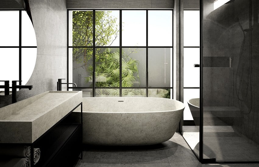 Современный интерьер ванной комнаты с каменной ванной, бетонной стеной и полом и большим окном