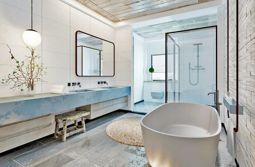 Ванная комната с каменной и плиточной стеной, подвесным светильником, ванной из каменной смолы и кафельным полом.