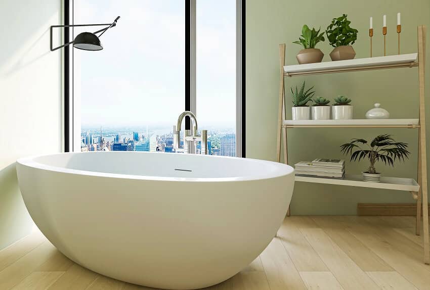 Ванная комната с отдельно стоящей ванной из каменной смолы, настенной лампой и полками с растениями.