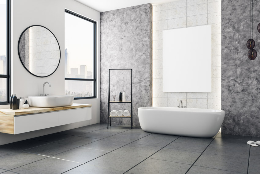 Красивая ванная комната с полом из сланцевой плитки, ванной, акцентной стеной, раковиной, зеркалом и окнами.