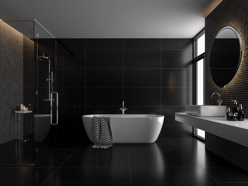 Черная ванная комната с акриловой ванной, душевой, стеклянной перегородкой, зеркалом, раковиной и столешницей.