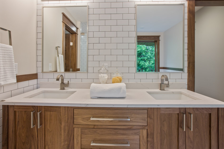 Туалетный столик в ванной комнате с плиткой в ​​стиле метро, ​​зеркалами, раковиной и деревянными шкафчиками