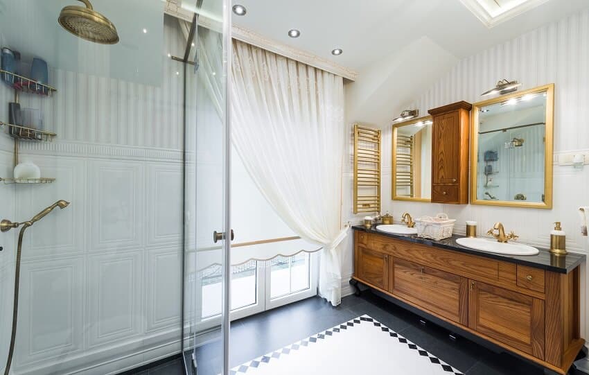 Современный интерьер ванной комнаты с плиточным полом, черным окном столешницы с занавесками и латунными аксессуарами для ванной комнаты