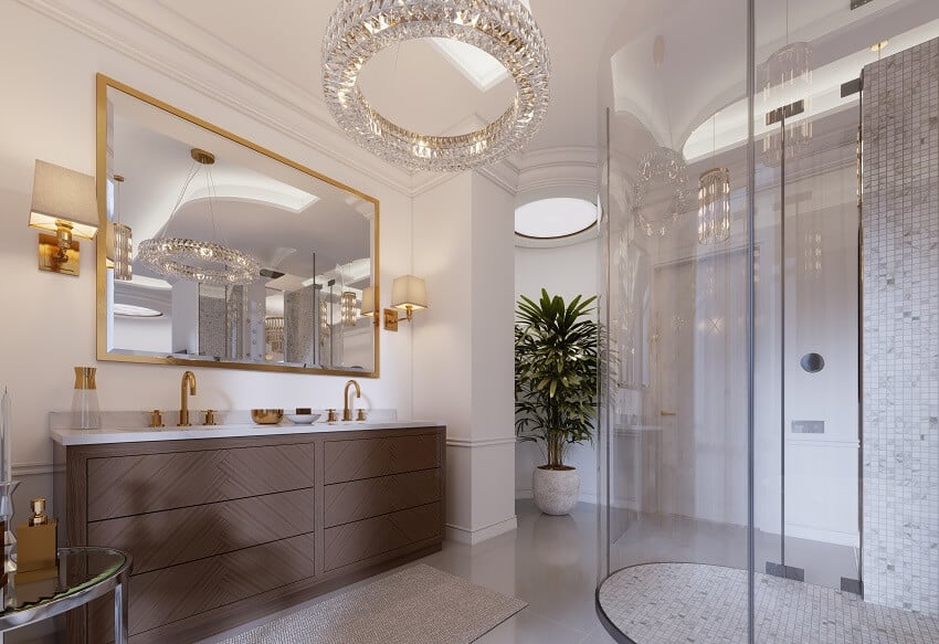 Современная ванная комната с туалетным столиком и зеркалом в золотой раме с бра на стене низкий столик с декором душ люстра растение и латунные ручки раковины
