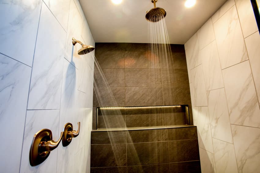Ванная комната с мраморной стеной, латунными насадками для душа и потолочным освещением