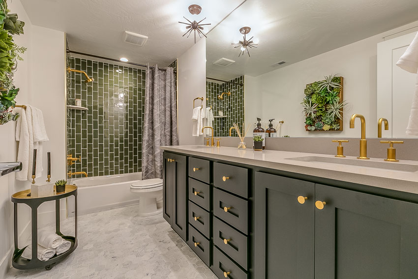 Ванная комната с зелеными шкафами, душевая плитка, латунная сантехника, зеркало, столешница, потолочный светильник