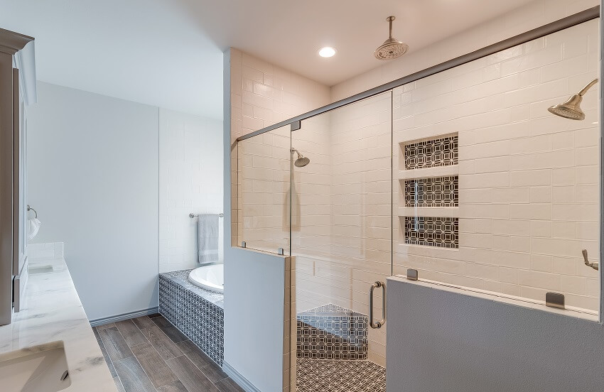 Ванная комната с огромной душевой комнатой с тремя душевыми лейками, узорчатым плиточным полом, раковинами из кирпичной стены и ванной.