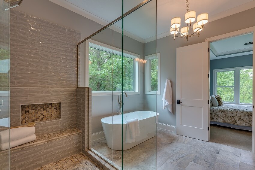 Спальня соединена с просторной ванной комнатой с люстрой, большой стеклянной душевой кабиной и отдельно стоящей ванной.
