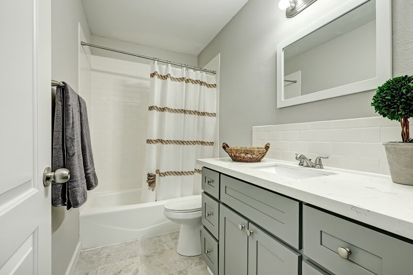 Интерьер ванной комнаты может похвастаться серебристо-серым туалетным столиком с мраморной столешницей и белым фартуком.