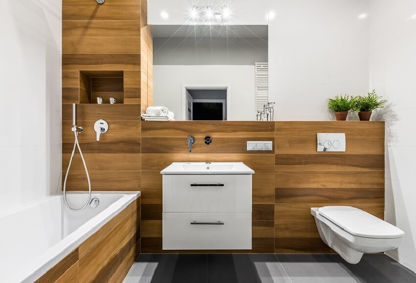 Современная деревянная ванная комната с стеновыми панелями из ПВХ, ванной, зеркалом, туалетом, шкафом и раковиной