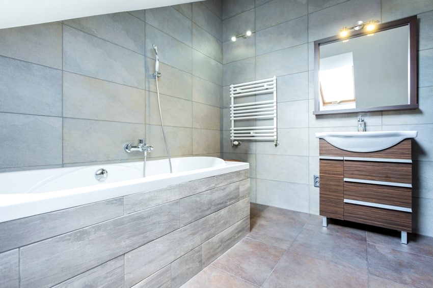 Полностью облицованный плиткой интерьер ванной комнаты с ванной и деревянной полкой