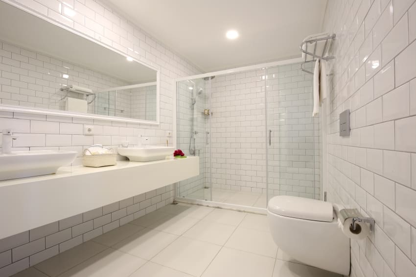 Белый полностью кафельный интерьер ванной комнаты с большим зеркалом