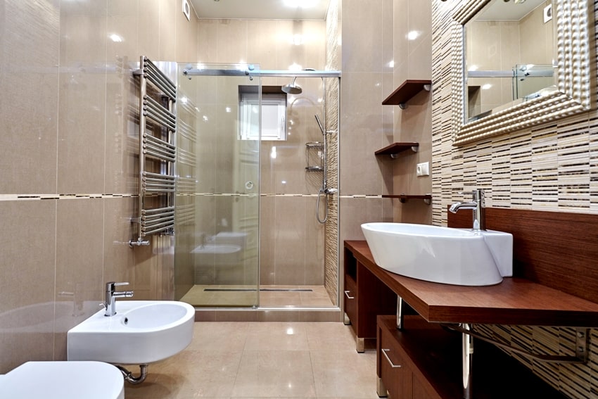Красивый полностью выложенный плиткой интерьер ванной комнаты с деревянными полками и шкафами