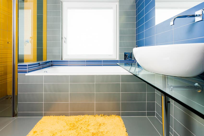 Ванная комната с серой плиткой, раковиной, стеклянным разделительным ковриком